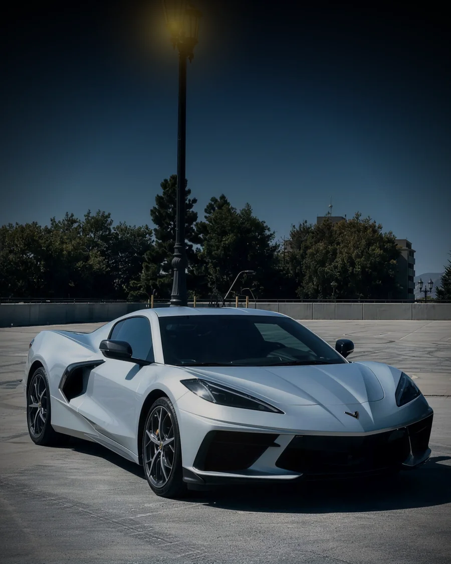 Chevrolet Corvette C8 blanco, premio real de la primera edición, bajo un farol encendido